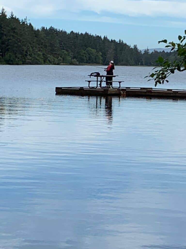 Angler fishing from a dock at Coffenbury Lake in Fort Stevens State Park