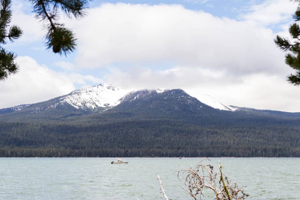 An fishing boat on diamond lake beneath diamond peak.