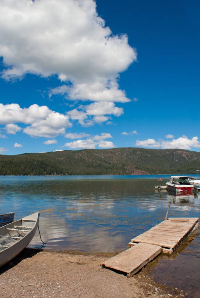 Paulina Lake dock with mountains and white clouds in background.