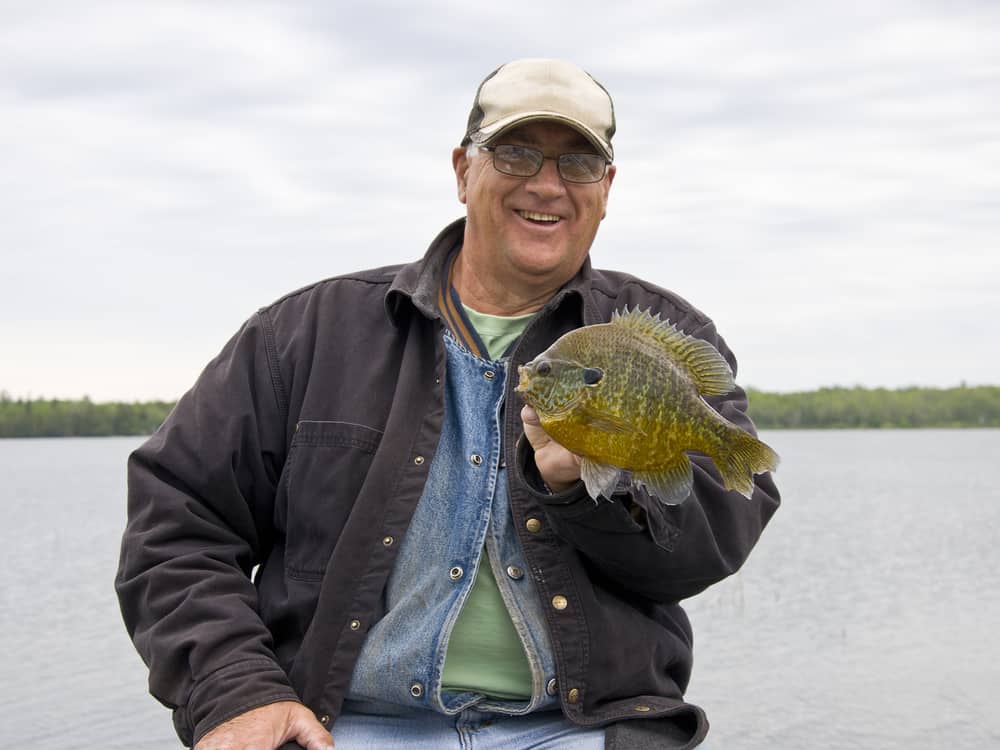 An angler holding a bluegill caught in a large lake.