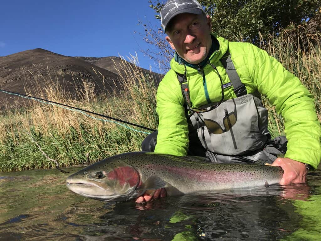 An angler holding a summer steelhead caught on the deschutes river in the fall.