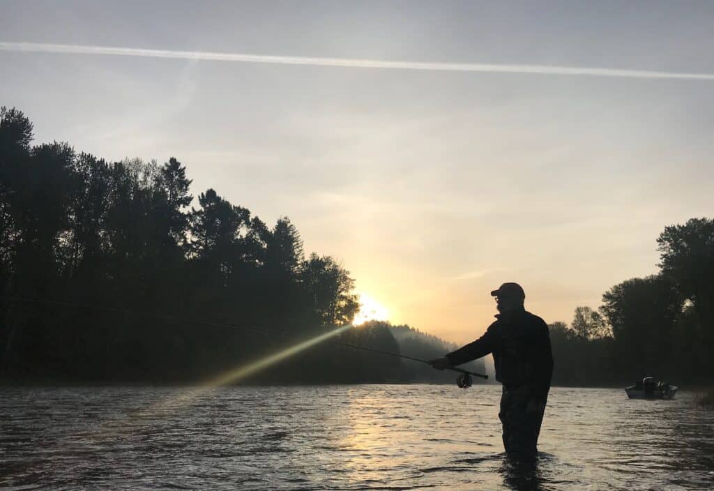 Un pêcheur à la mouche jette dans la rivière clackamas à silhouette