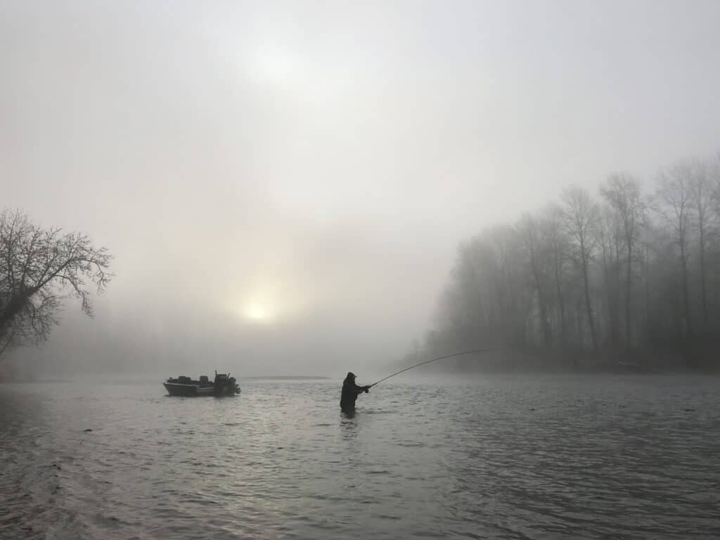 Fly fisherman casts on a foggy day.