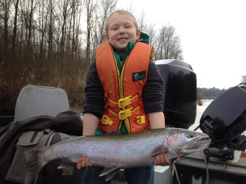 A boy holding a clackamas river steelhead.