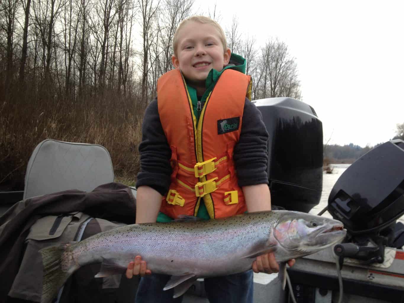 A kid holding large clackamas river steelhead.