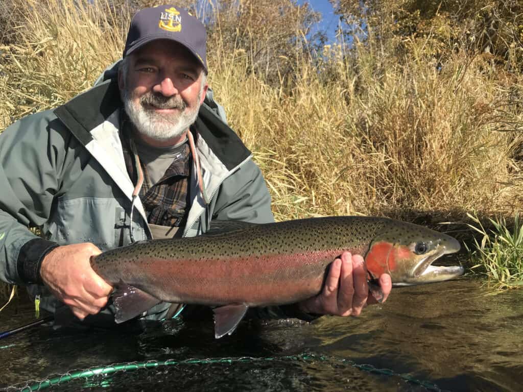 Man holds a beautifully colored steelhead caught in the deschutes river.