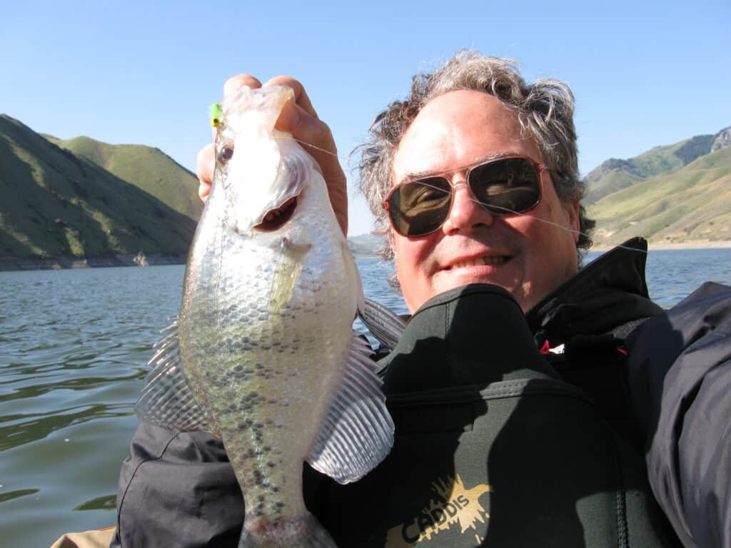 Angler in float tube holds up a large white crappie he caught fishing at Brownlee Reservoir in Eastern Oregon.