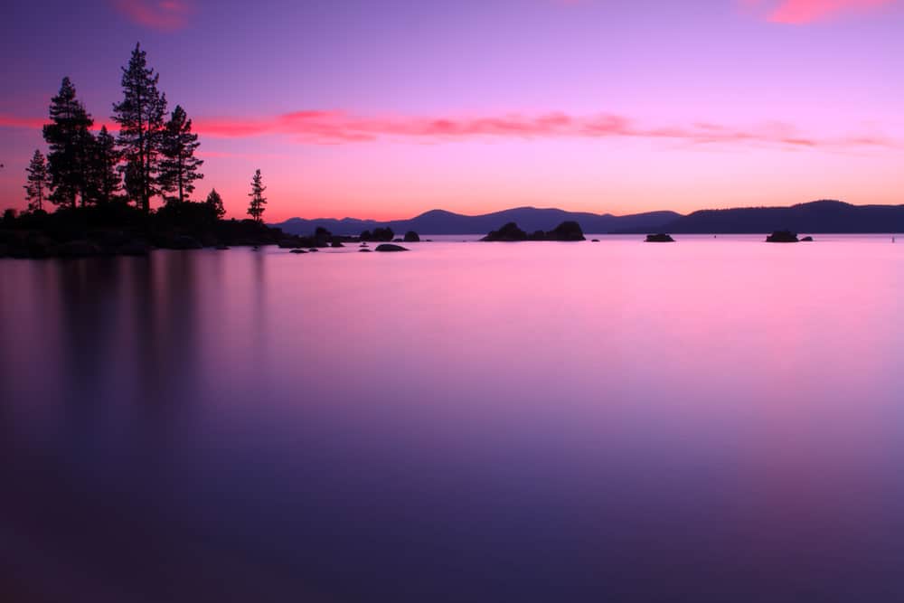 A scenic photo of Lake Tahoe with deep purples and pinks at sunset.