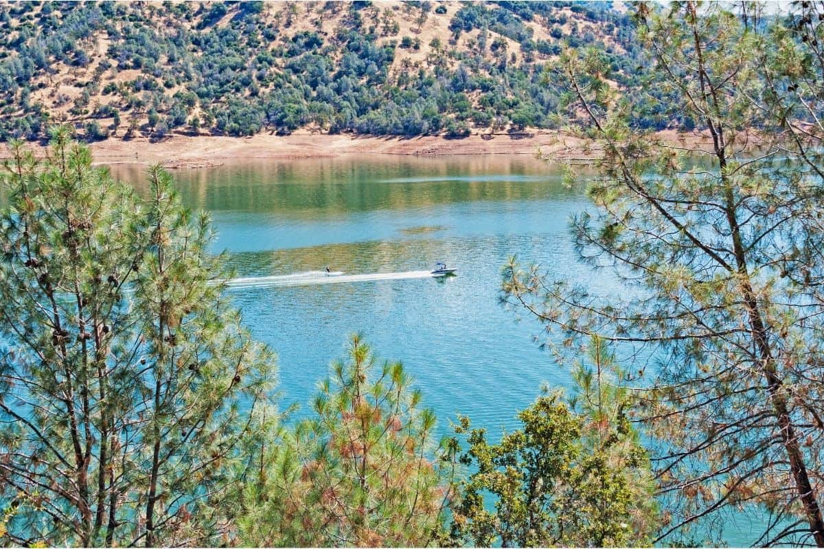 A boat speeds across the surface of Don Pedro Lake.