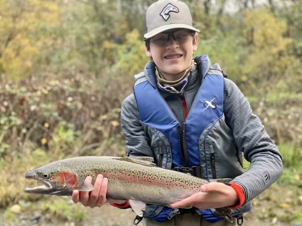 A boy holds a large steelhead he caught fishing in the Trinity River in California.