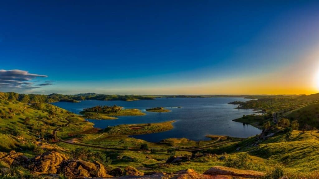 A scenic overview of Millerton Lake from a distance with the sun low in the sky.