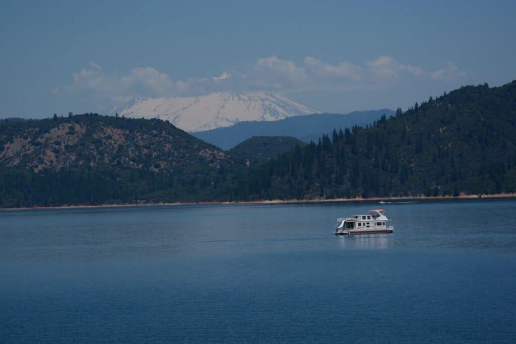 A houseboat motors slowly across Shasta Lake.