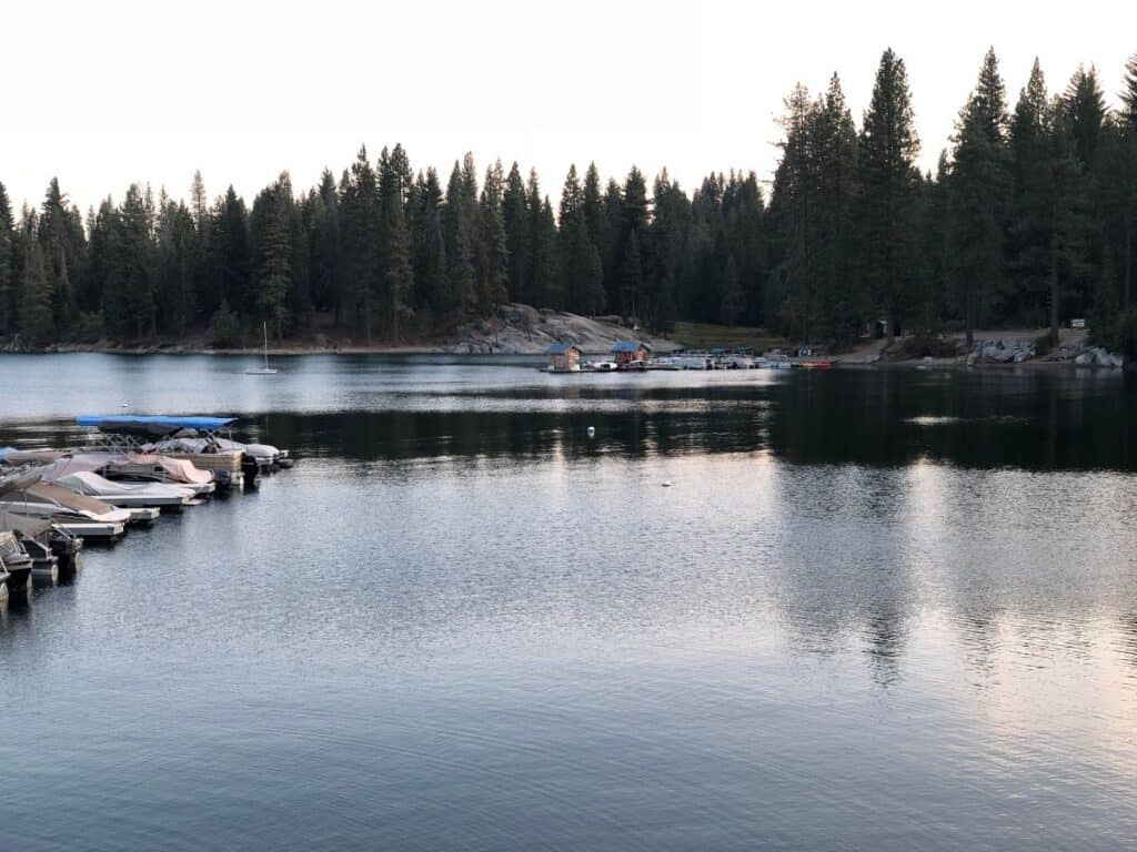 A fishing boat motors past over moored boats at the marina at Shaver Lake.