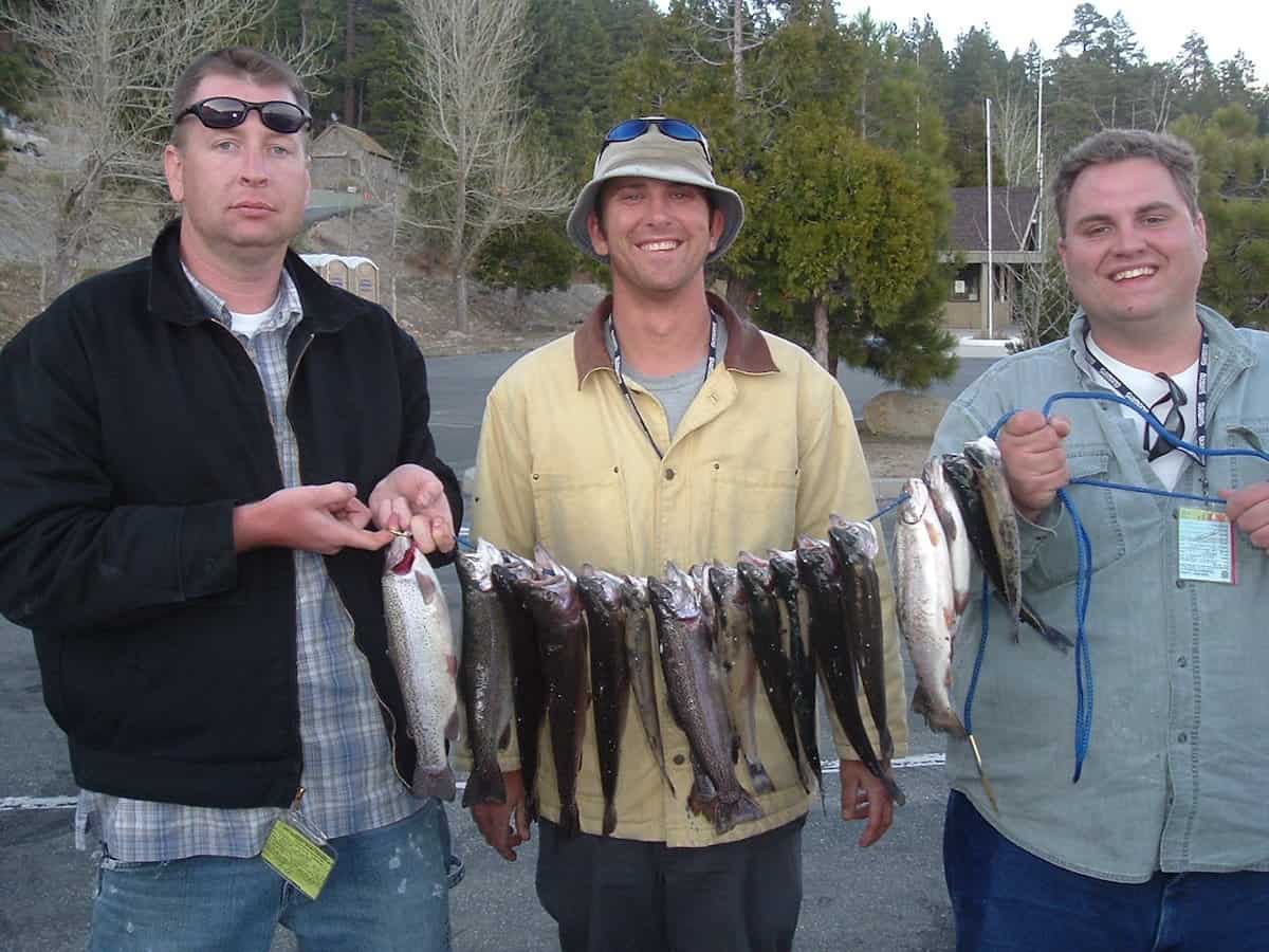 Three happy anglers hold a stringer full of trout they caught fishing at Big Bear Lake, California.