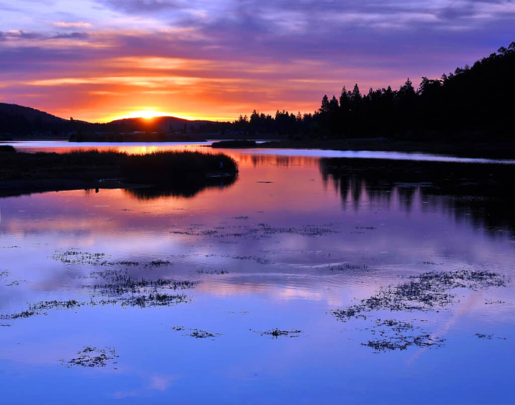 Spectacular sunrise over Big Bear Lake, showing shades of orange, yellow, blue and purple.
