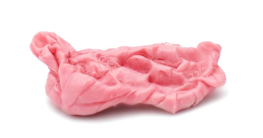 A chewed piece of pink chewing gum isolated on white.