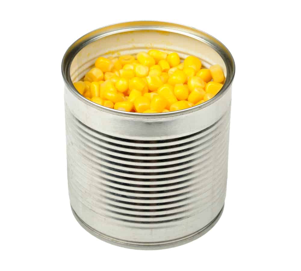 An open can showing yellow corn inside on a white background.