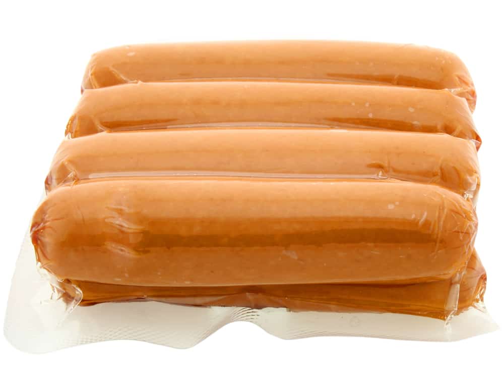 A package of raw hot dogs on a white background.