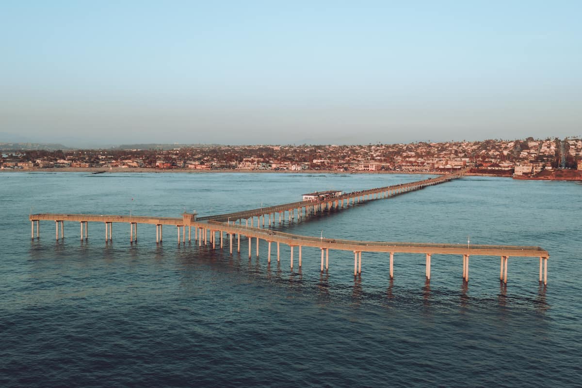 Aerial view of Ocean Beach Pier in San Diego, looking back with view of coast and city.