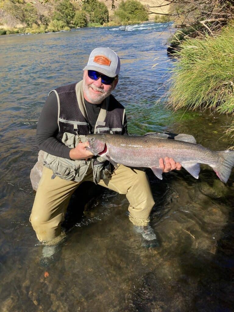 An angler holding a very large hatchery summer steelhead caught while fishing in the Deschutes River in Oregon.