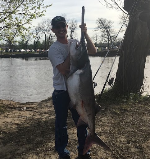 A man holds up a paddlefish snagged in one of Oklahoma's best spoonbill fishing spots.