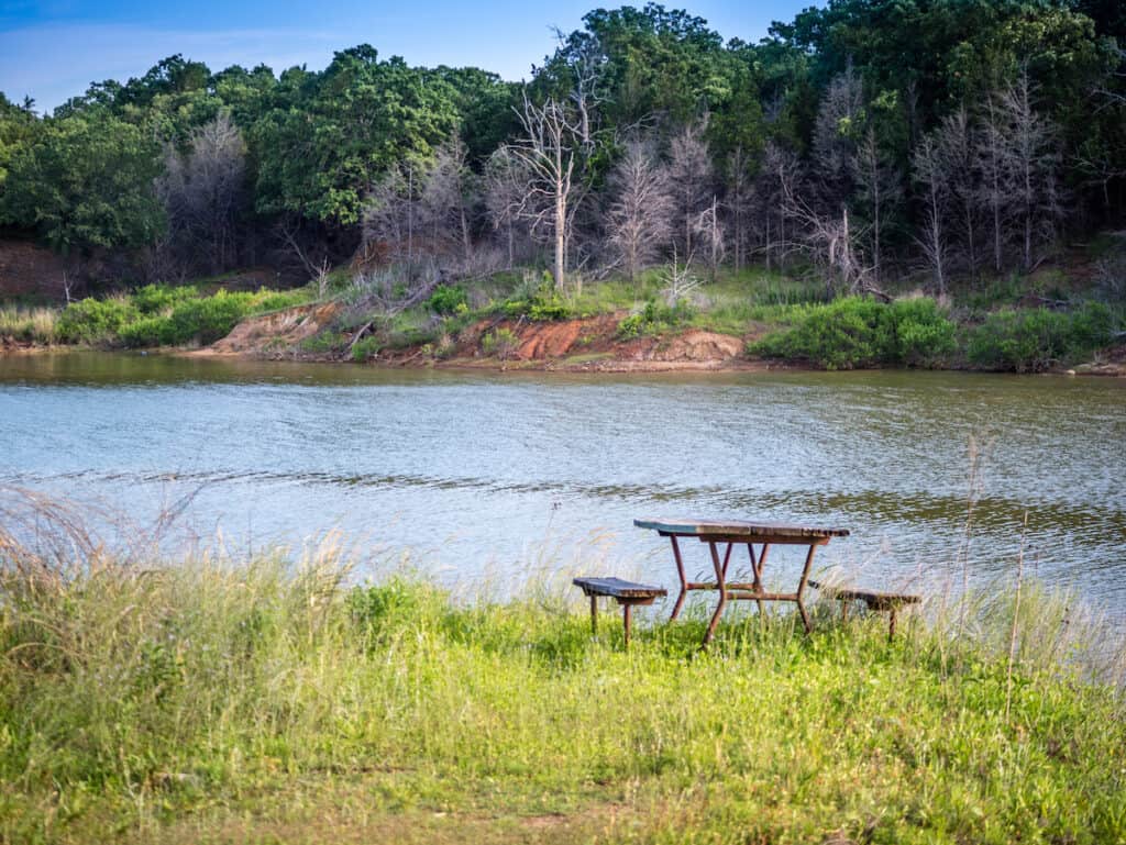 a picnic table sits on the grassy banks of Lake Texoma, a popular fishing spot on the border between Texas and Oklahoma.