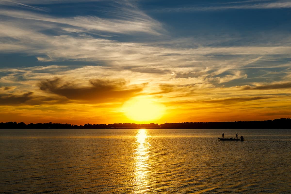 The setting sun highlights a silhouette of a fishing boat on Lake Thunderbird in Oklahoma.