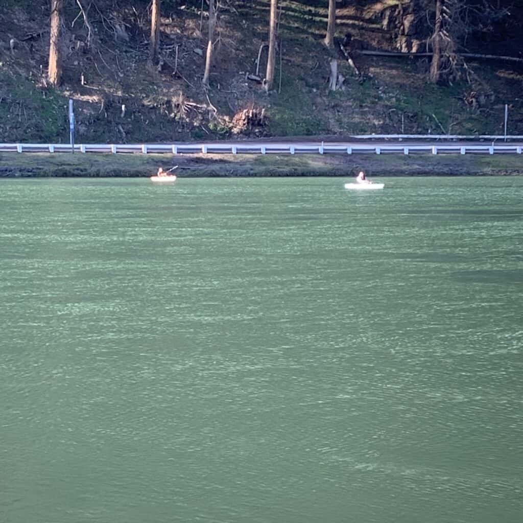 Two kayakers cast for rainbow trout on a sunny winter day at Leaburg Lake on the McKenzie River in Oregon.