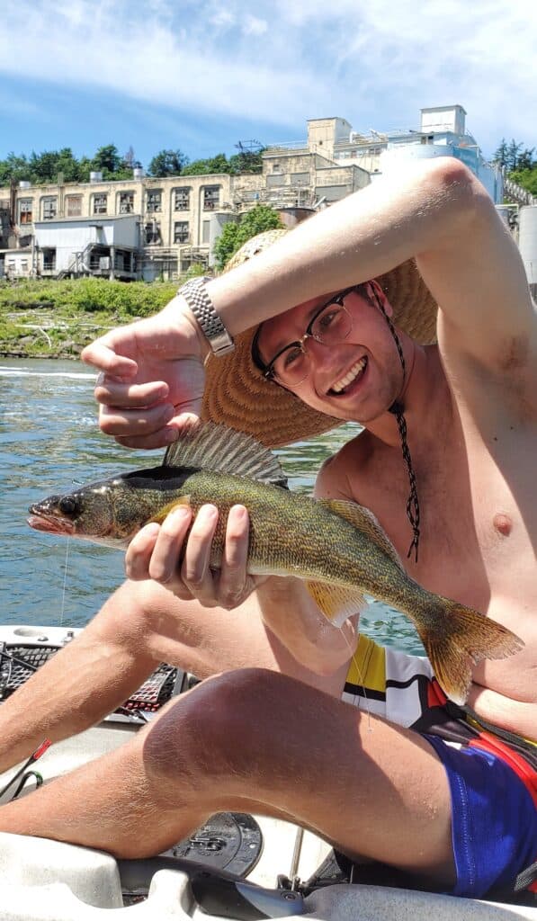 An angler in a kayak holds a walleye he caught on the Willamette River below Willamette Falls.