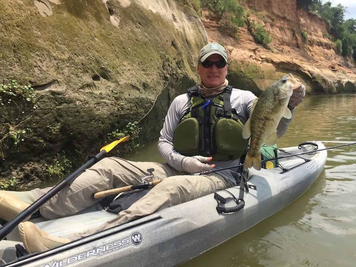 An angler in a kayak shows a Guadalupe bass caught in Texas.