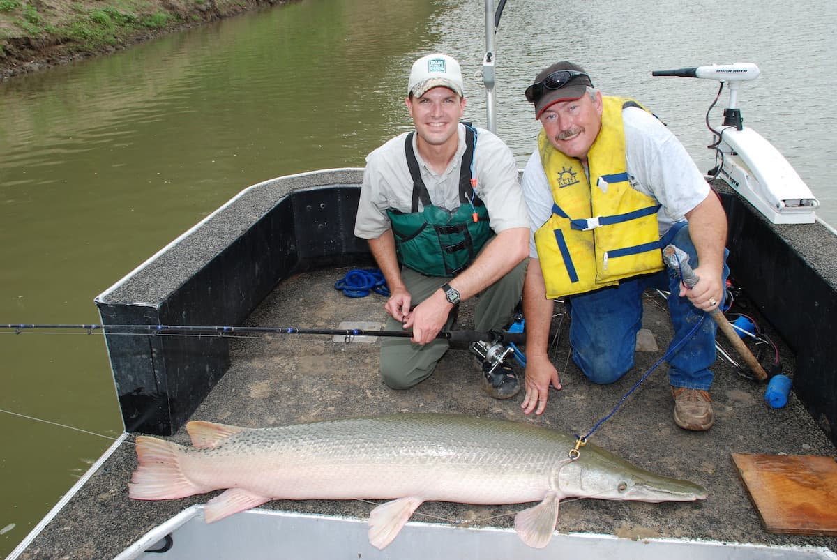Two anglers with a large gar caught fishing from a boat in Texas.