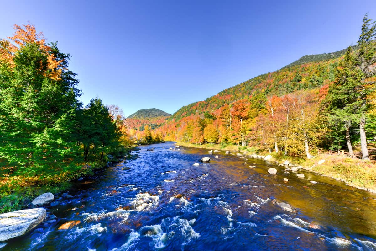 Fall colors in the trees frame the rushing blue waters of the West Branch Ausable River, a prime New York trout stream.