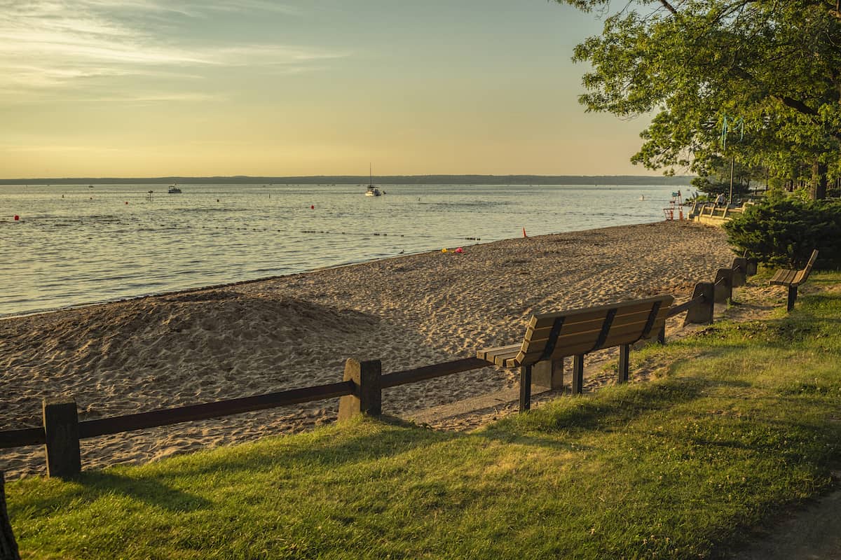 A park in the foreground with a fishing boat on the surface of Oneida Lake, a popular walleye fishing spot.