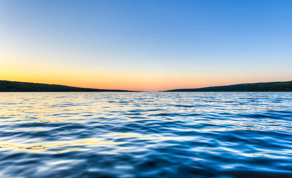 The blue water of Seneca Lake below and the blue sky above with the yellow light of dusk between.