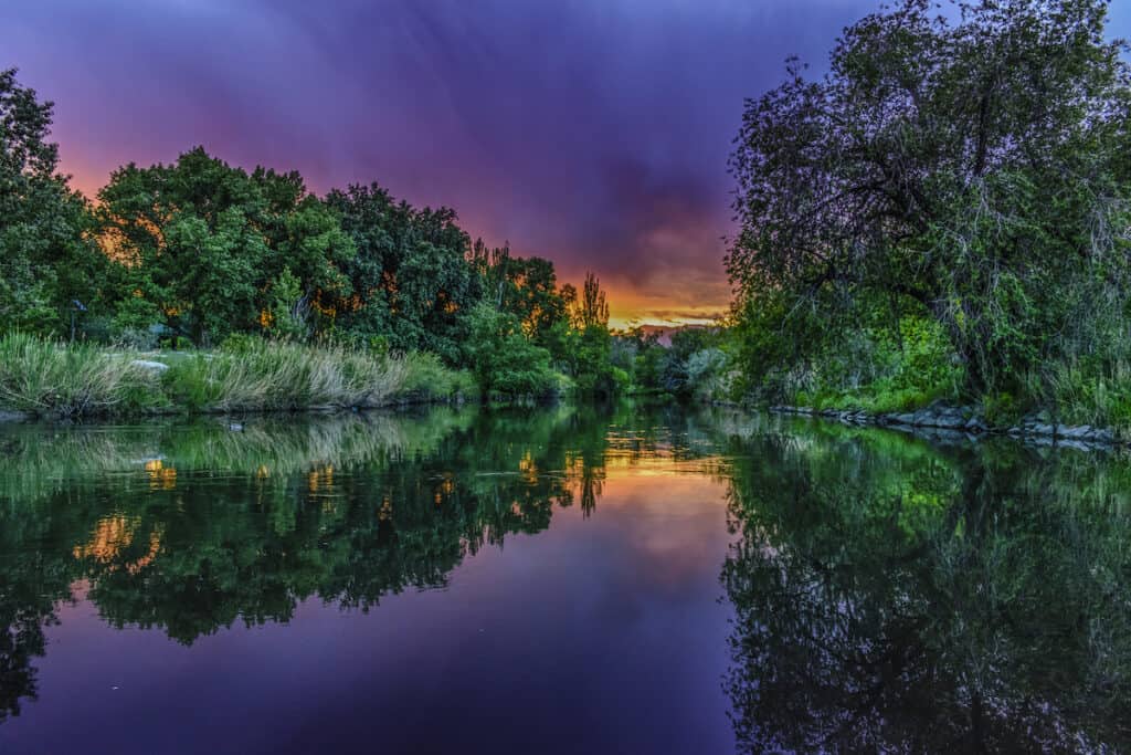 The Jordan River in Utah, slowly flowing in the darkening evening sky.