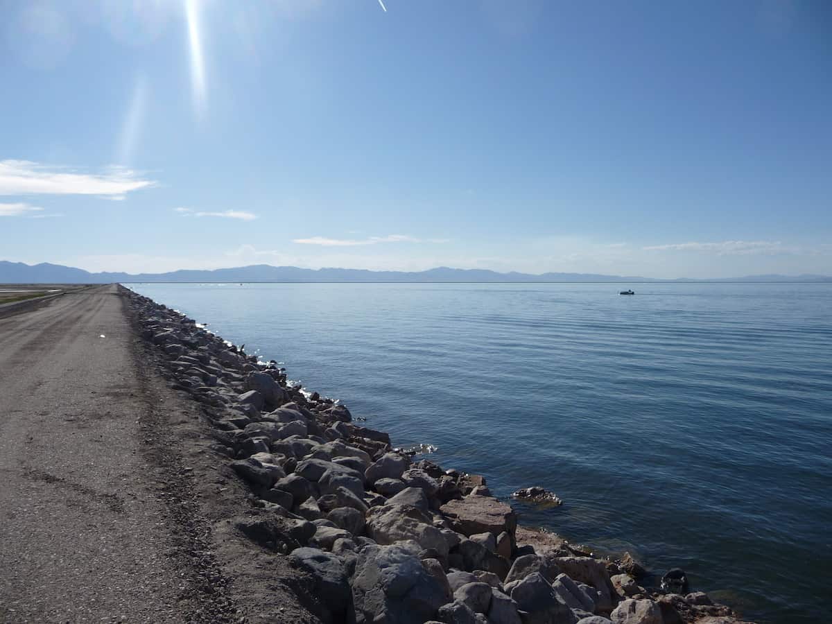 A fishing boat in the distance with the rocky dike along Willard Bay Reservoir, a great wiper fishing lake in Utah.