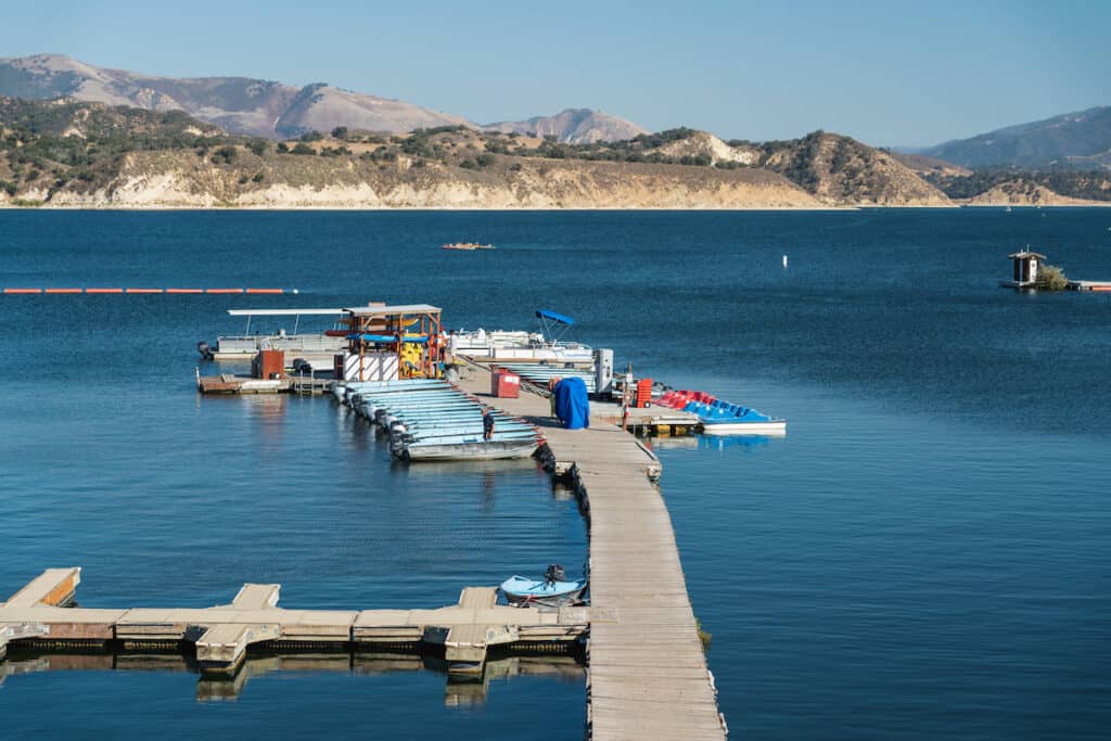 A dock with fishing boats on the blue water of Cachuma Lake.