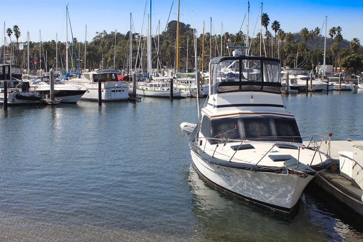 A fishing boat in the foreground and sailboats in the background at Santa Barbara Harbor.