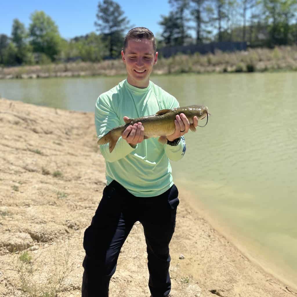 Fisherman on the bank holding a catfish caught in Louisiana.