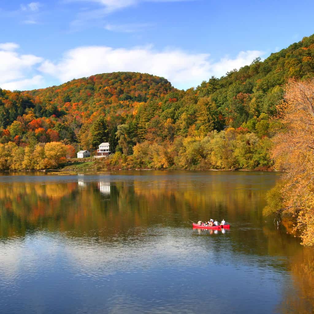 A red boat on the Allegheny River with fall colors along the shore.