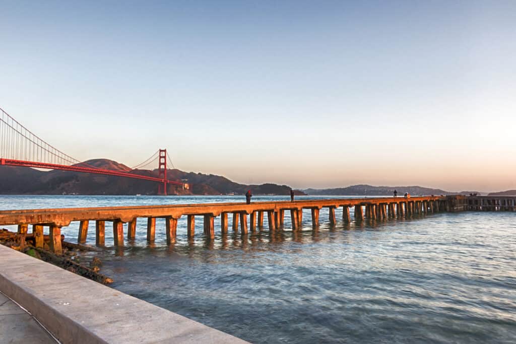 Fishermen at Torpedo Wharf in San Francisco try to catch fish very early in the morning, with the Golden Gate Bridge in the background.