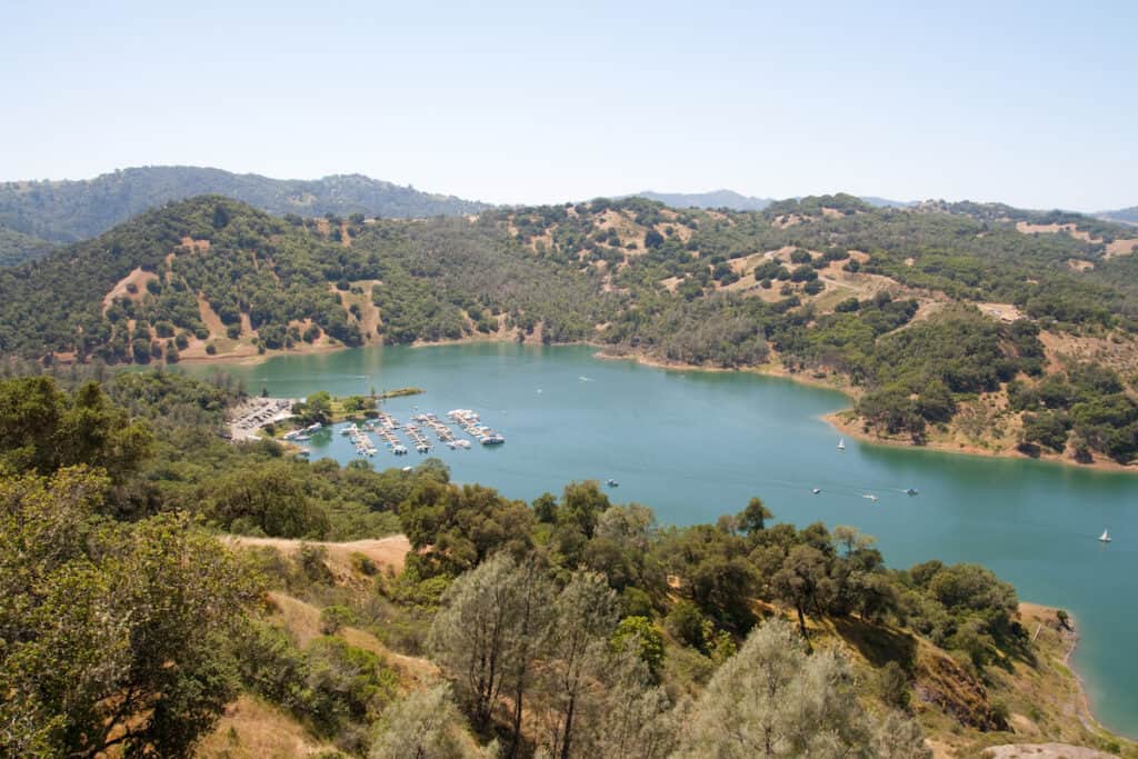 A view of Sonoma Lake from top of a mountain showing fishing boats and other watercraft in a marina and elsewhere on the lake.