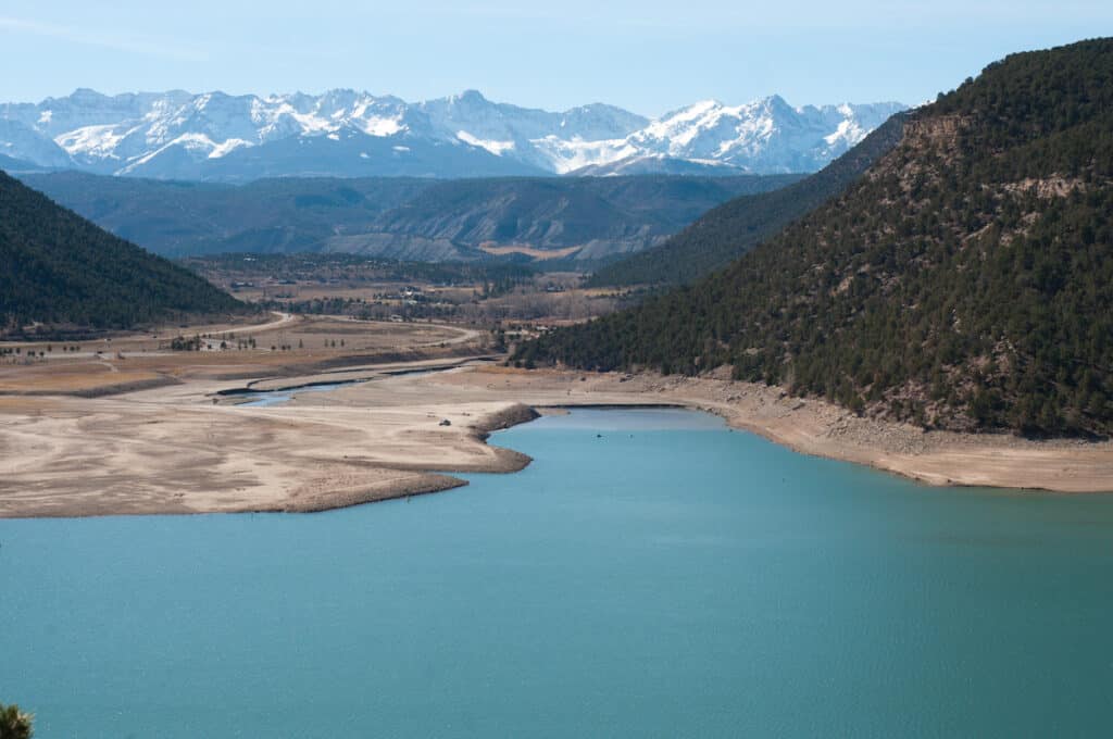 Aerial photograph of blue water and light shorelines during low water drought conditions at Ridgway Reservoir.