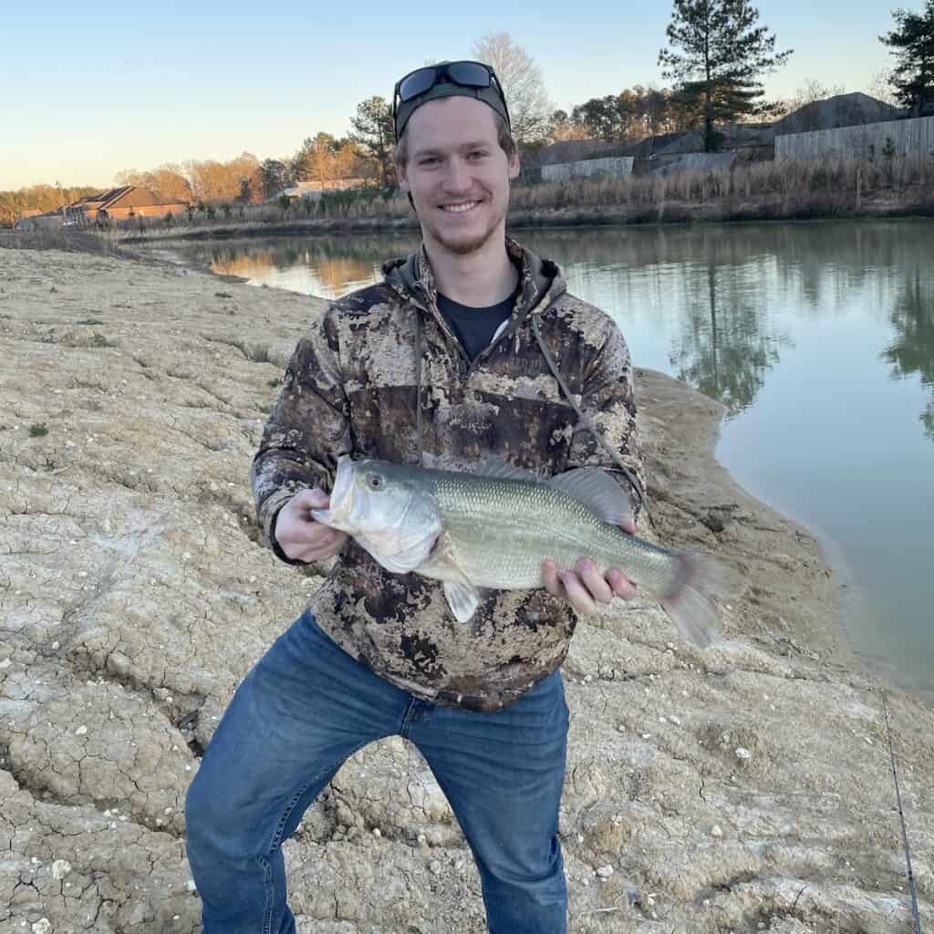 Lake Cataouatche (lake, cataouatche, best bass fishing lakes, Louisiana Cypress Bayou Reservoir) An angler holds a largemouth bass caught in Louisiana, with the water in the background.