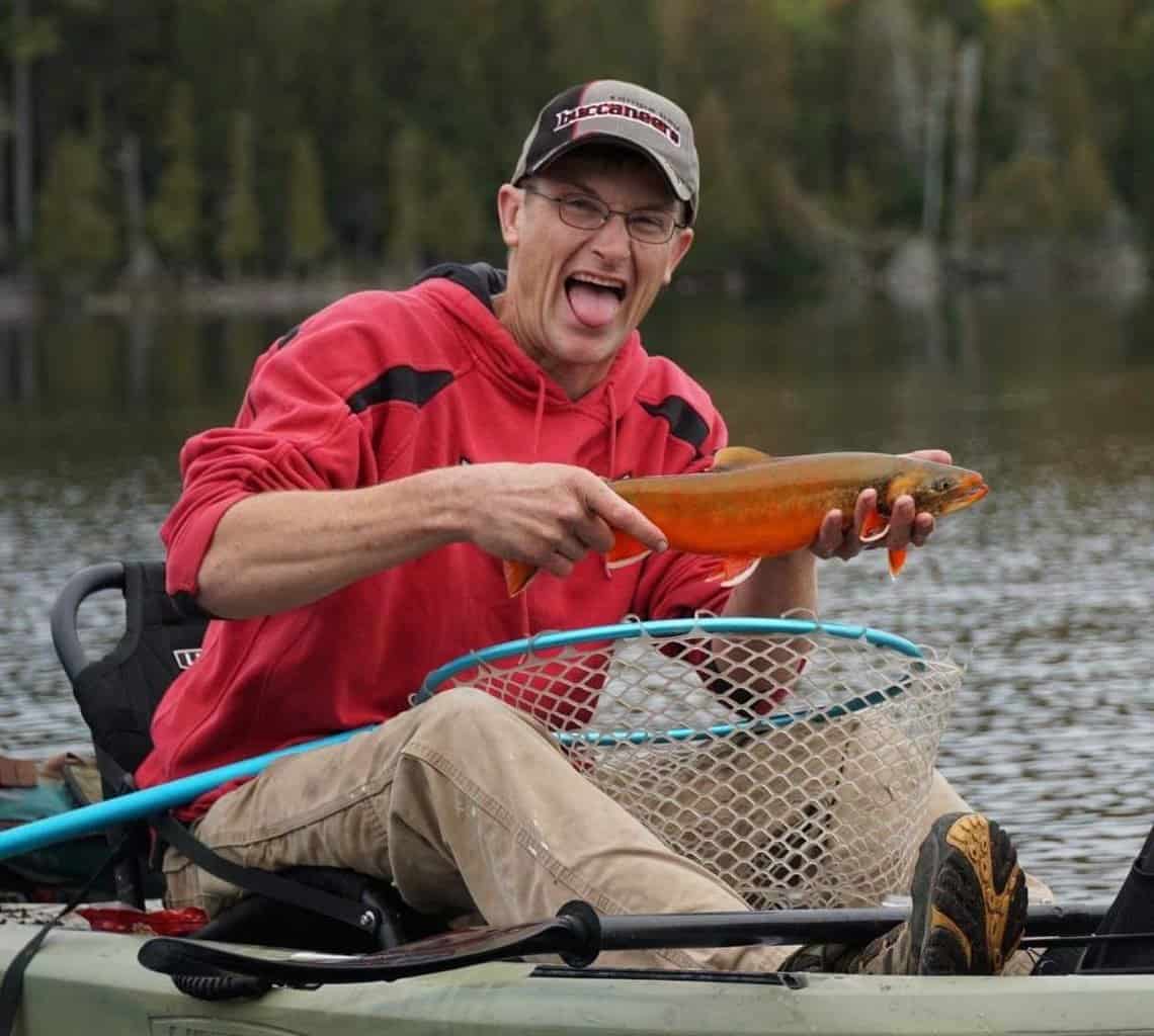 Stan Williams holds a bright red colored charr he caught fishing in northern Maine.