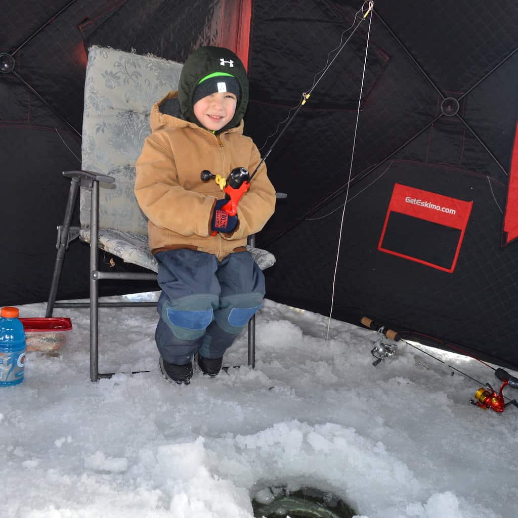 A boy ice fishing in a hole while inside a hut during the Long Lake Ice Fishing Derby in Maine.