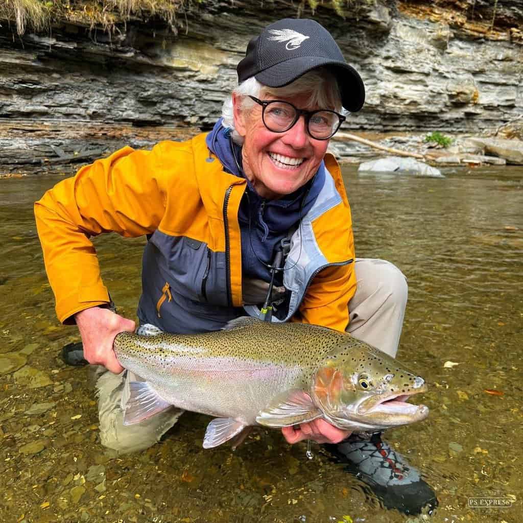 Woman anglers holds a nice steelhead above the water of Cattaraugus Creek, New York.