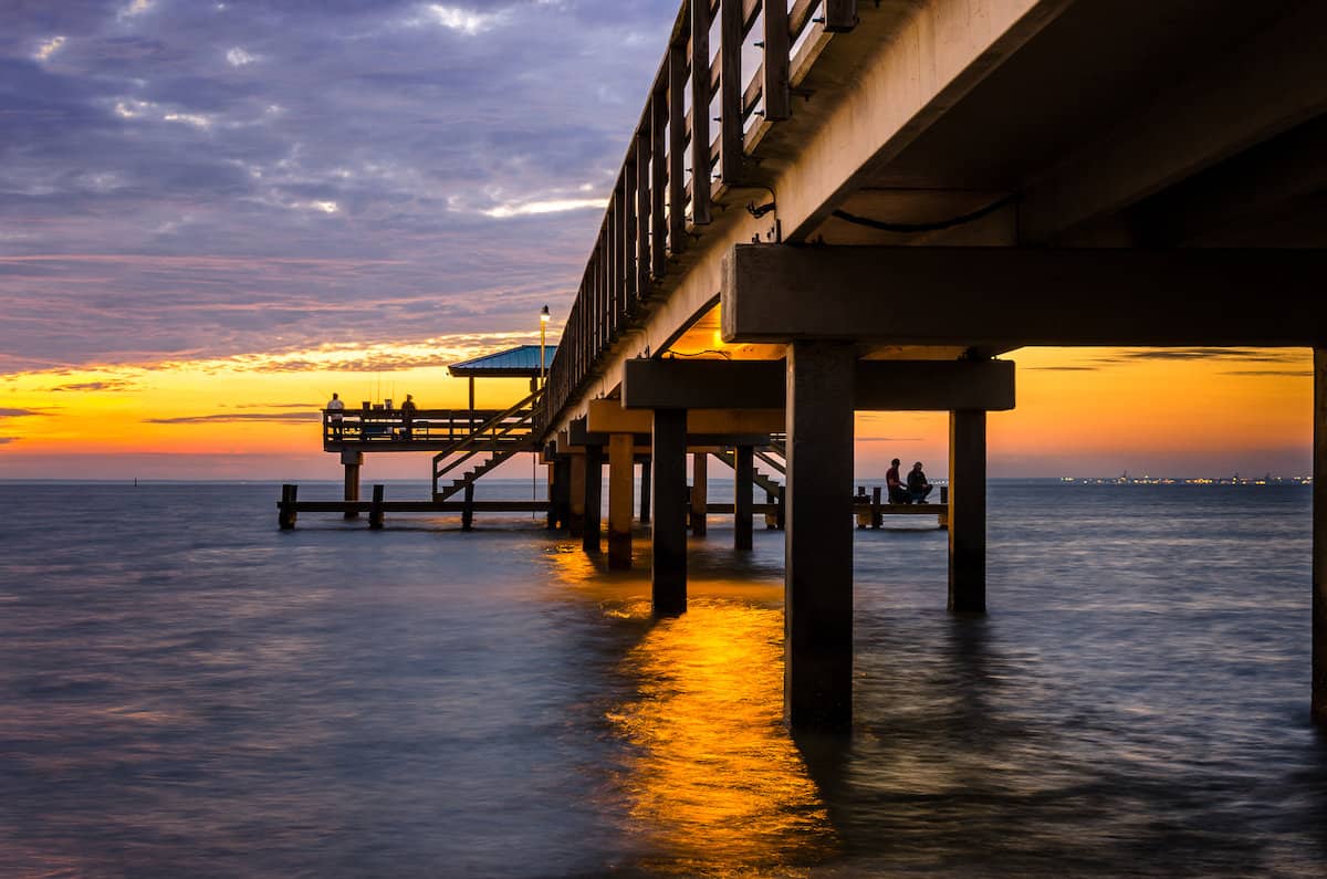 The orange light of sunset basks a fishing pier on the Alabama Gulf Coast, where redfish fishing is excellent.