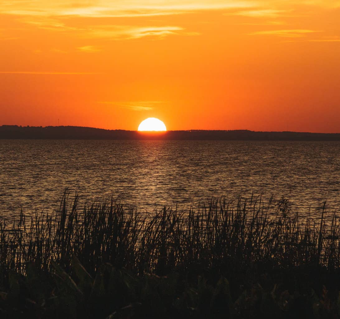 A bright orange sun sets behind Lake Apopka, one of Orlando's best bass fishing lakes.