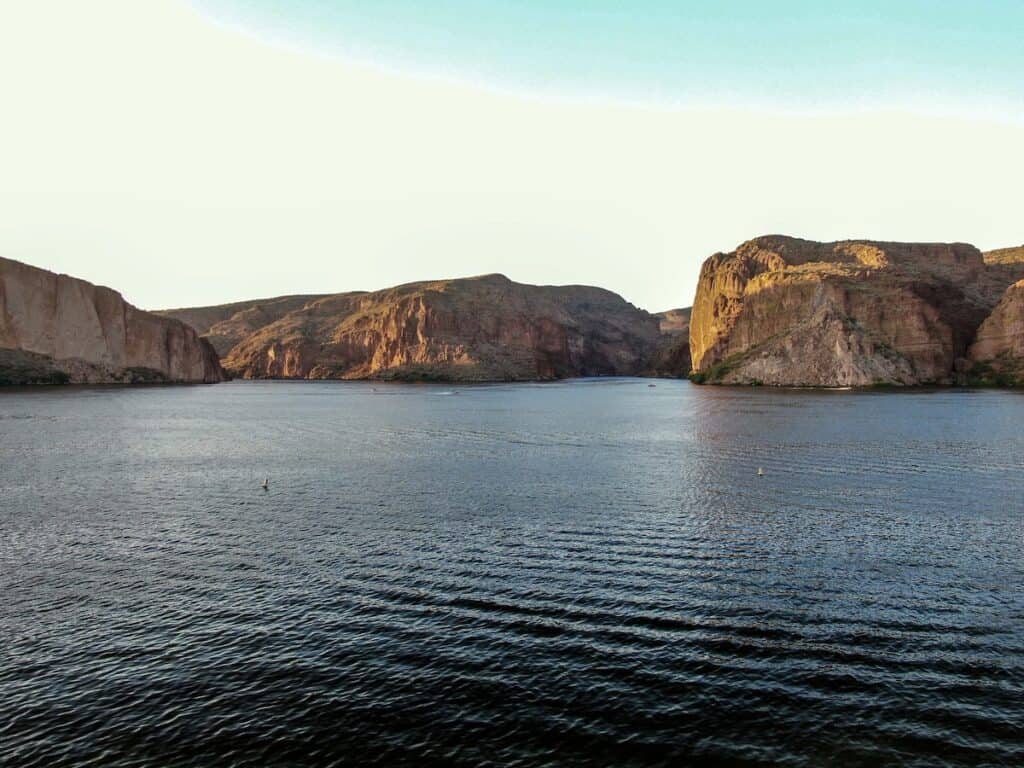 Ripples across Canyon Lake with steep rock formations and a few fishing boats in the background.